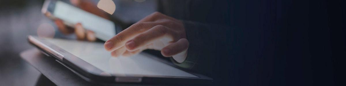 a hand typing on a keyboard, another holding a smartphone