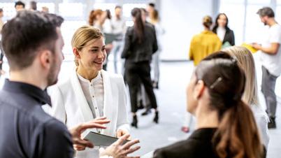 A group of business people networking in small groups within a large open space